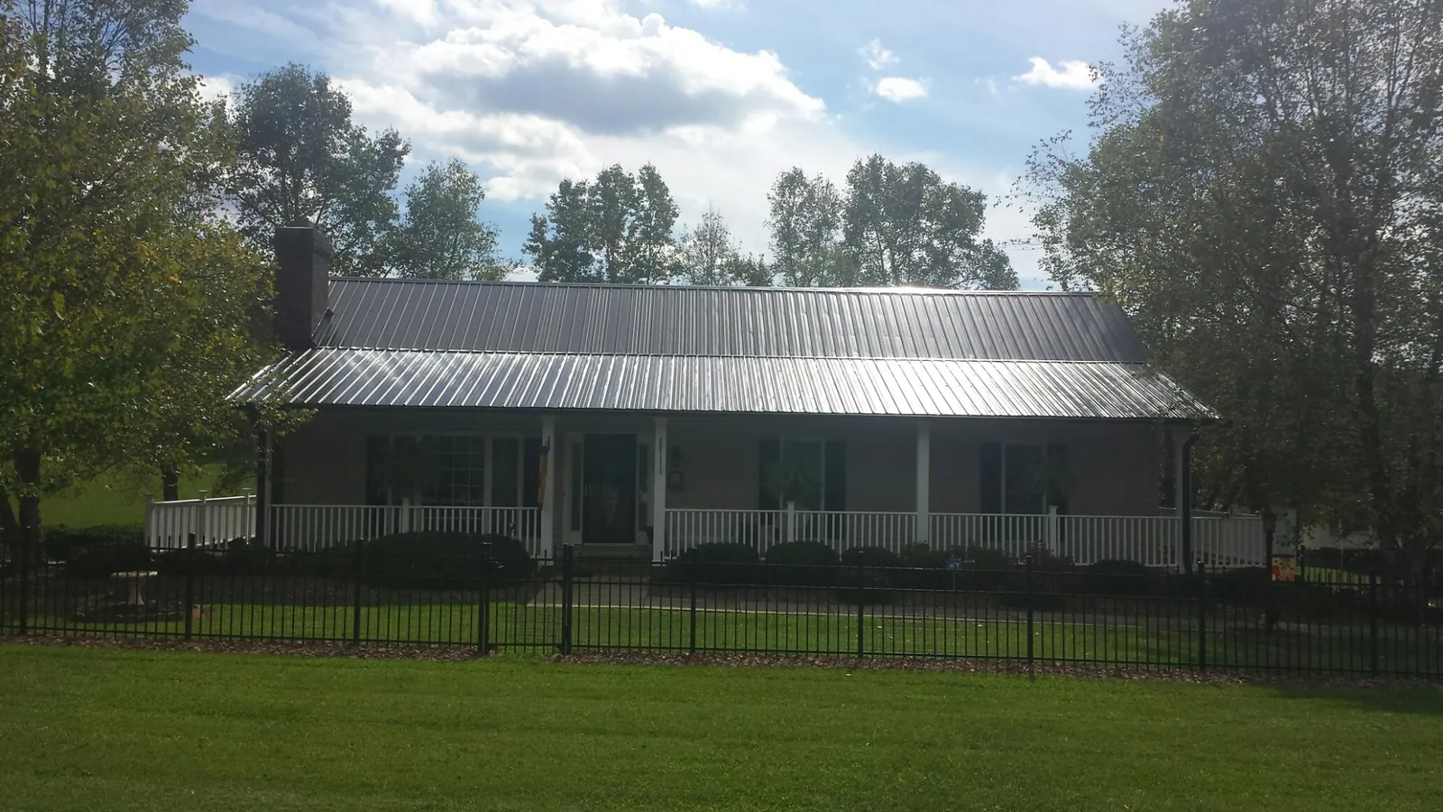 Gray metal roof on a brick ranch with a full width front porch — Gutter Guard Installation work by our crew in Everson