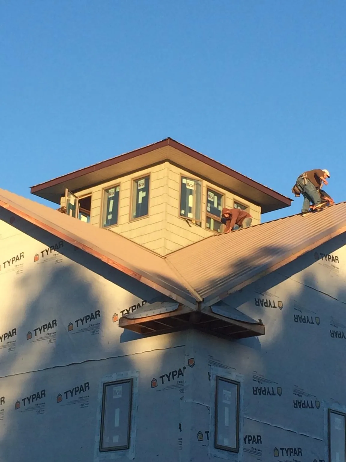 Roofers working around a rooftop cupola on a new metal roof at sunset — Roof Waterproofing in Everson by Roofing Brothers